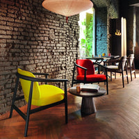 Vibrant yellow and red chairs against a rustic brick wall; modern design with a stylish wooden table.