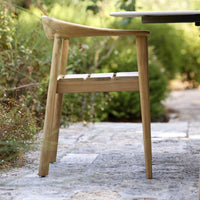 Natural wood chair with a smooth finish, showcasing light oak color and minimalist design, set against greenery.