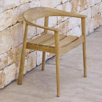Light wood chair with a smooth finish and minimalist design, featuring a natural grain pattern against a stone backdrop.