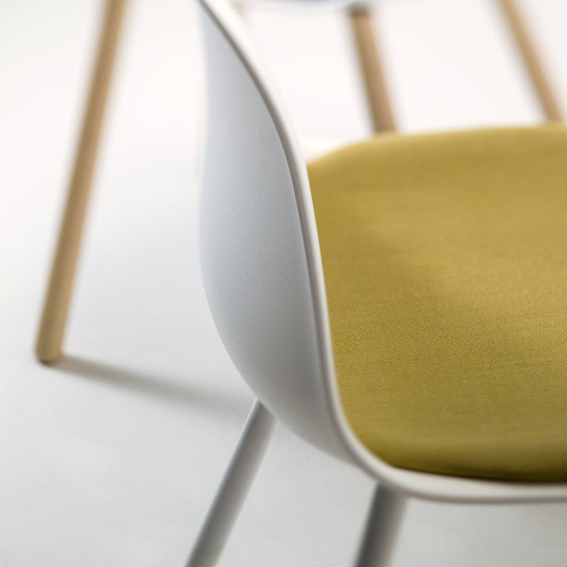 White chair with a soft yellow-green cushion, featuring a minimalist design and wooden legs. Perfect for modern decor.