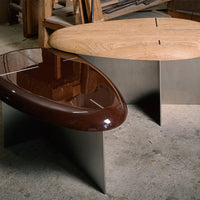 Brown glossy table and light wood table with sleek metallic bases, displaying modern design elements and smooth finishes.
