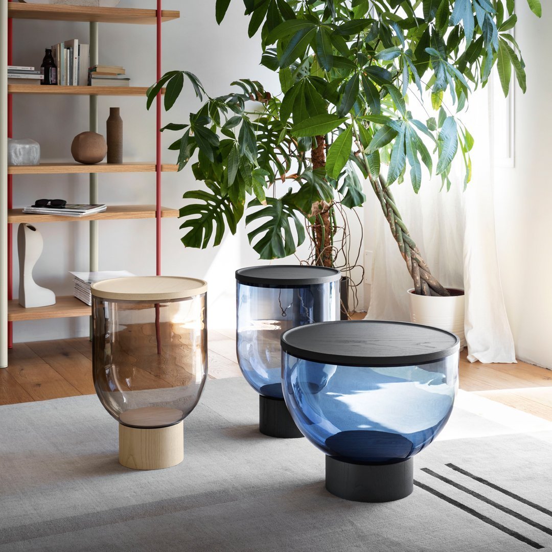 "Modern glass side tables in clear, smoke, and blue hues with minimalist designs and sleek finishes."