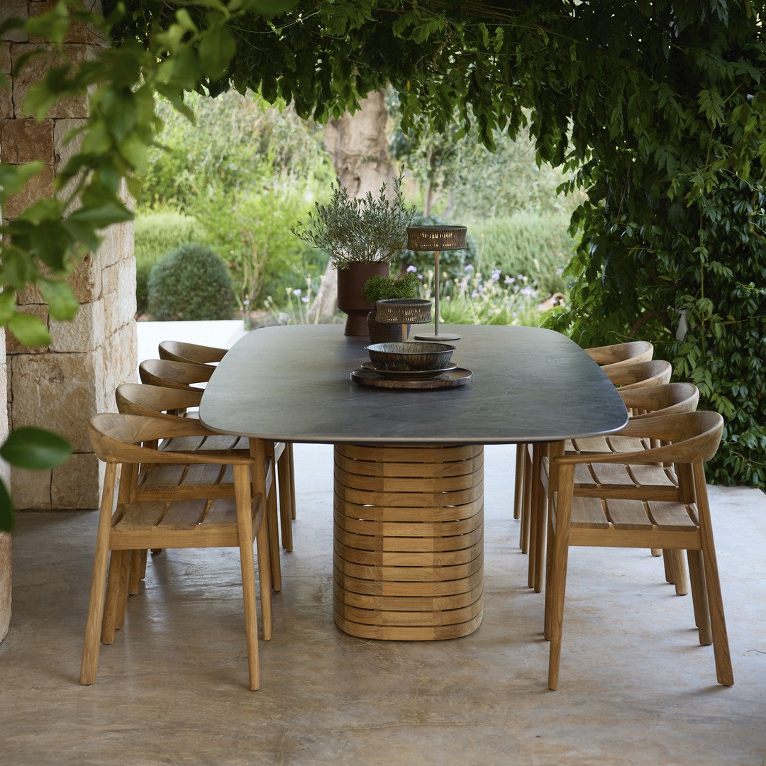 "Elegant black tabletop with natural wood tones and sleek, modern lines in a lush outdoor setting."