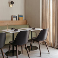 Modern dining setup with sleek black chairs, a light marble table, and soft beige walls, complemented by elegant textures.