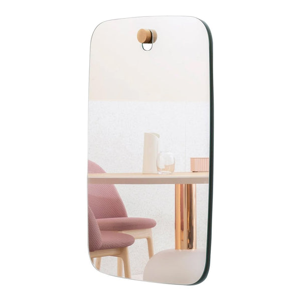 "Modern mirror with a sleek green edge, reflecting soft pink chairs and a stylish gold table accent."