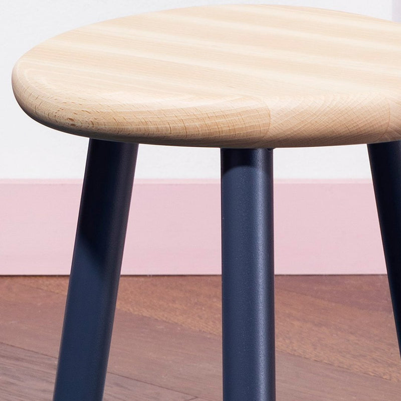 Natural wood top with subtle stripes, complemented by sleek navy legs and warm wood tones, against a soft pink backdrop.