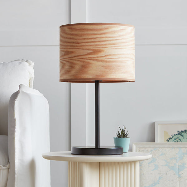 Wooden lampshade with a smooth light brown finish, paired with a sleek black metal base. Modern, minimalist design.