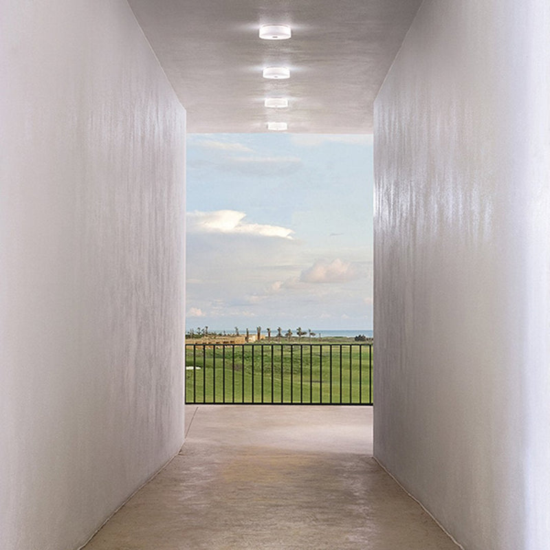"Bright white walls and soft natural light frame a serene green landscape beyond."
