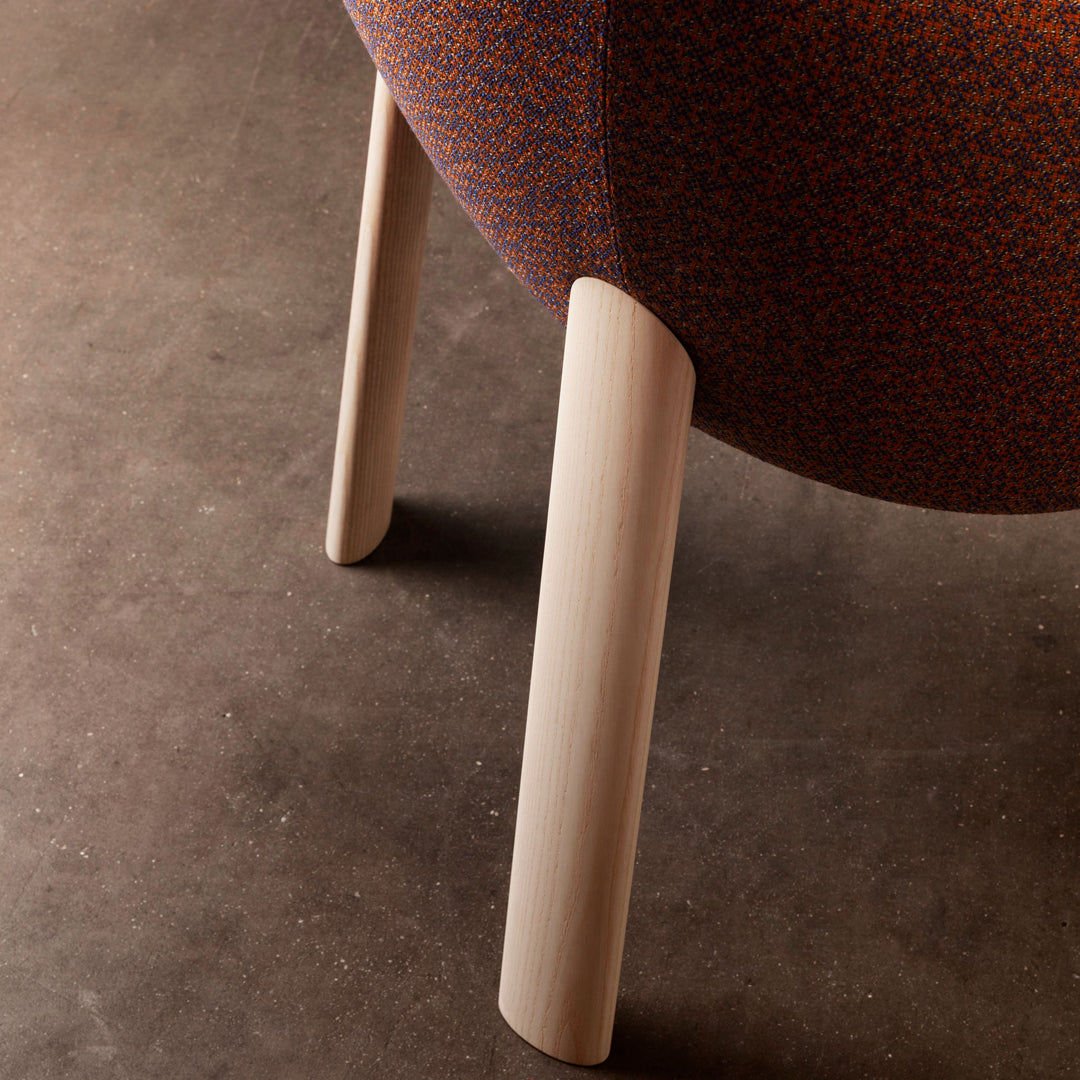 Rust-colored patterned upholstery with wooden legs on a minimalist chair, perfect for modern decor.