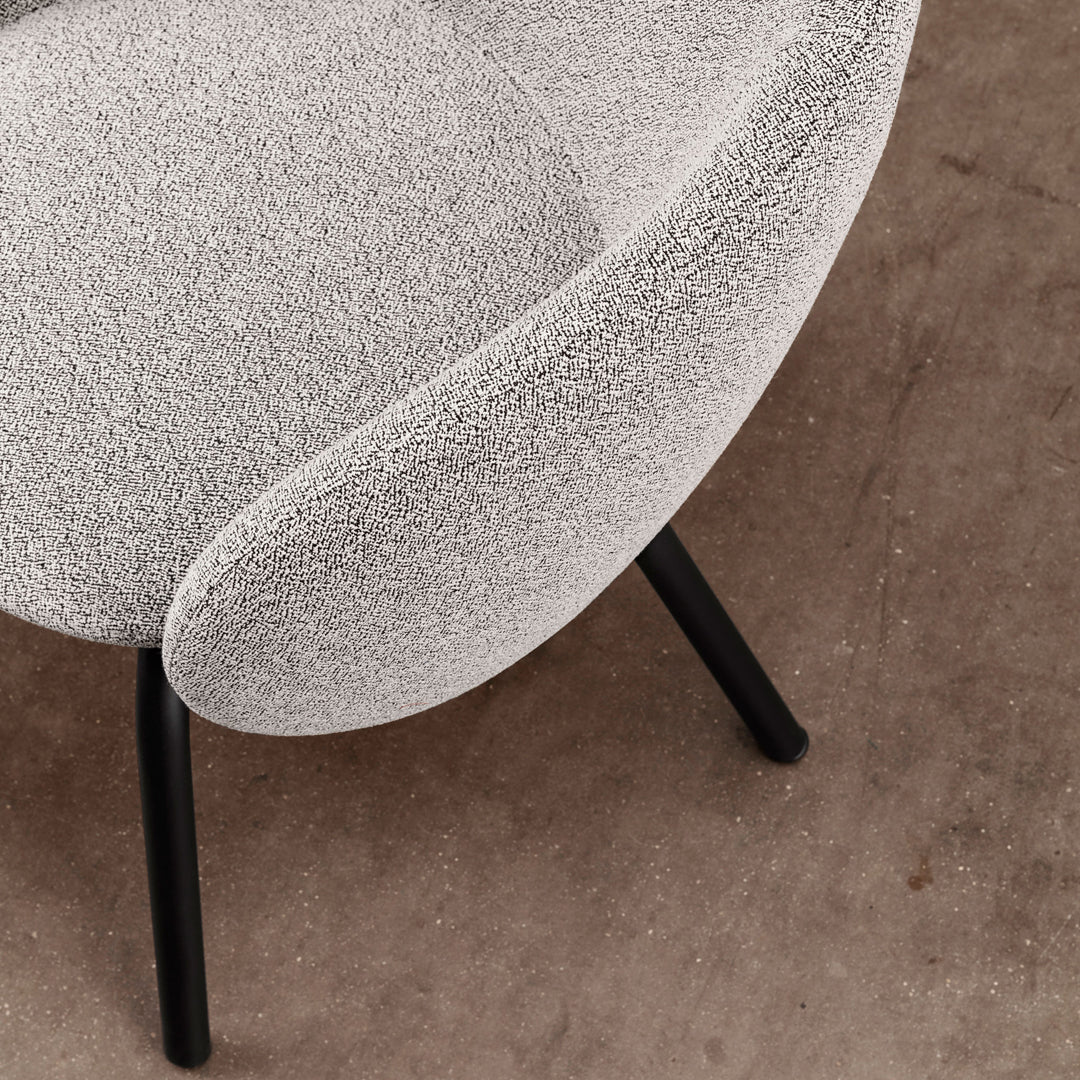Grey textured chair with curved design and black legs, set against a neutral background. Ideal for modern decor.