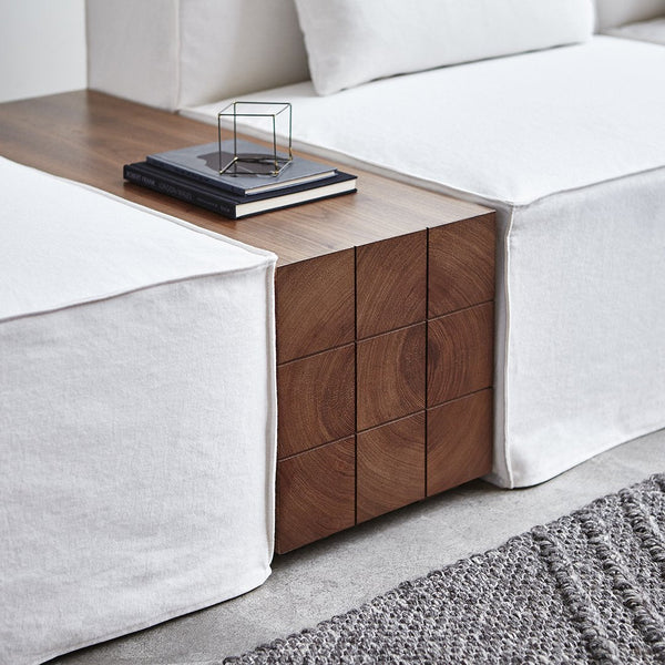 "Textured white fabric upholstery paired with rich wooden accents and a woven gray rug."