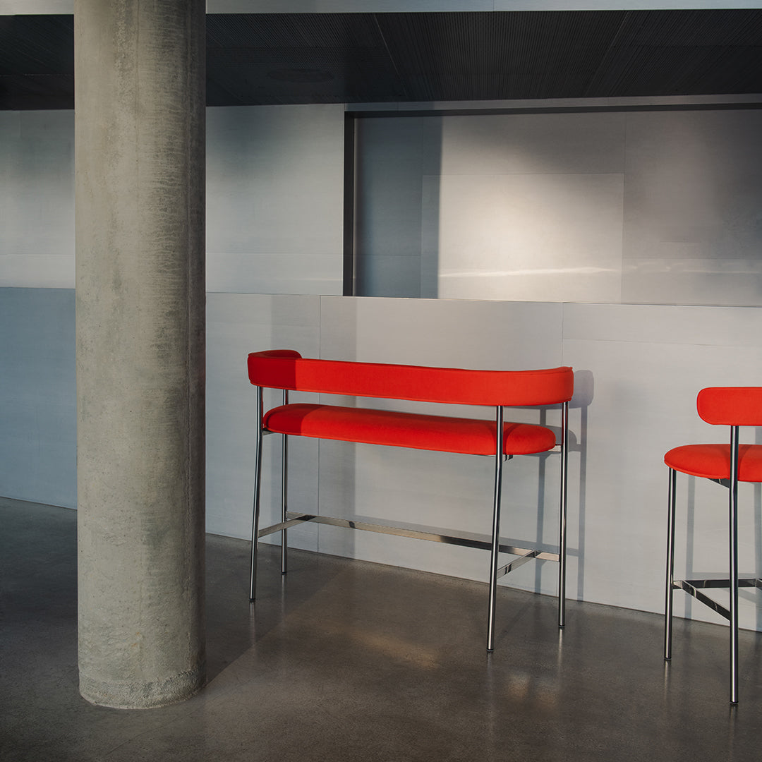 "Modern bar stools with vibrant red seats and sleek metal frames against a minimalist gray backdrop."