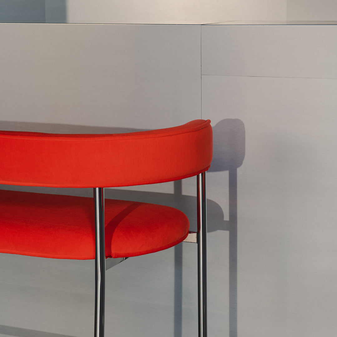 Vibrant red curved seat with sleek black legs against a soft gray background. Modern design for stylish interiors.