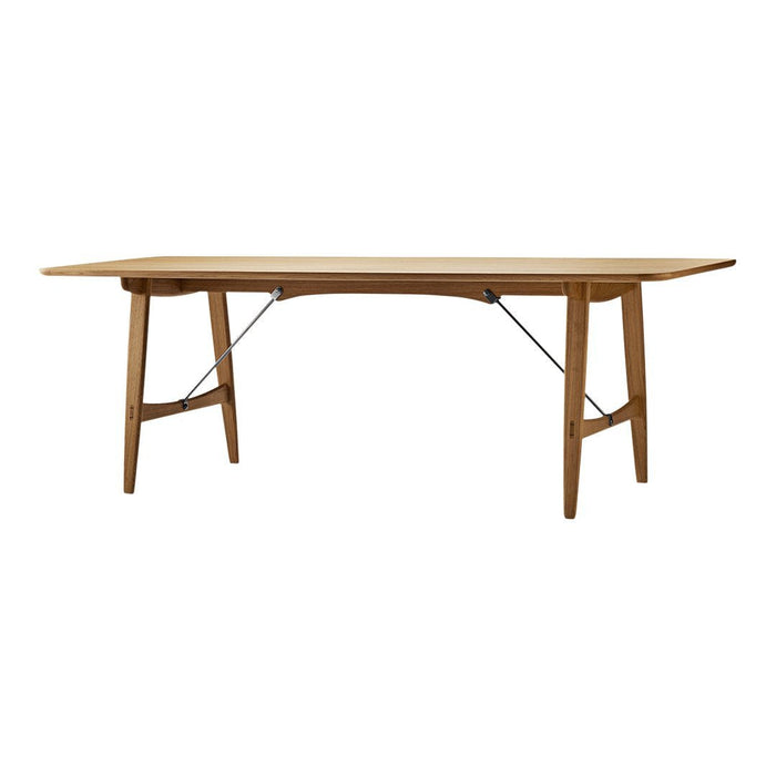 Natural wood dining table with a warm honey finish and a sleek, minimalist design, featuring solid legs and subtle metal accents.