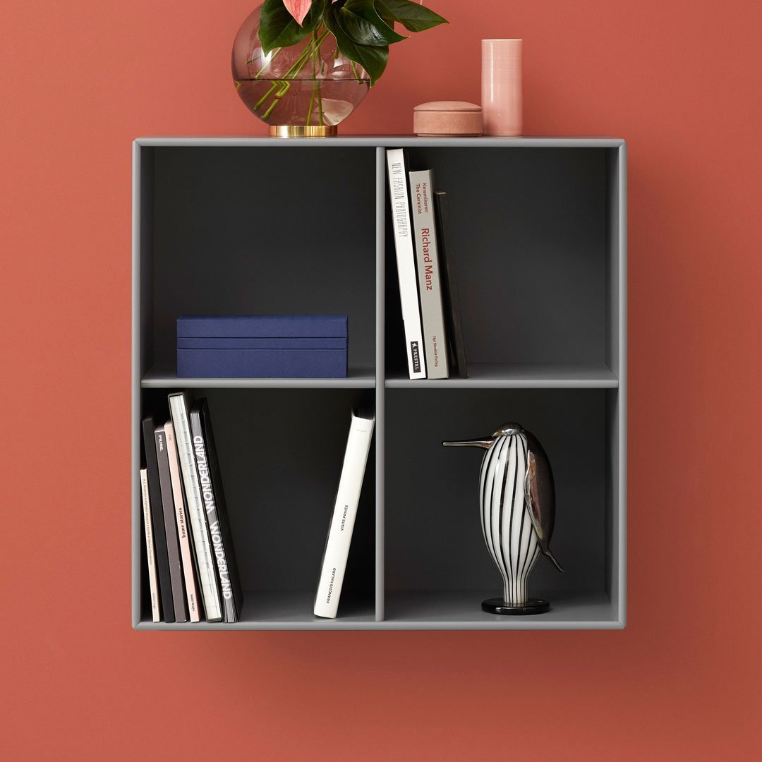 Gray modular shelving unit against a coral wall, featuring blue and pink accents with black-and-white items displayed.