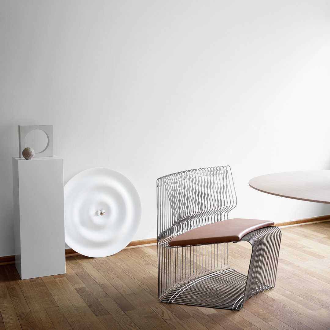 Modern wire chair with a sleek silver pattern and a warm brown seat, set against a minimalist white background.