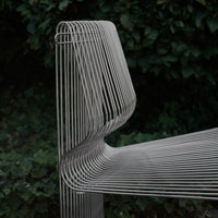 Sleek, modern metal bench with a minimalist design featuring gray lines and subtle curves against a dark green backdrop.
