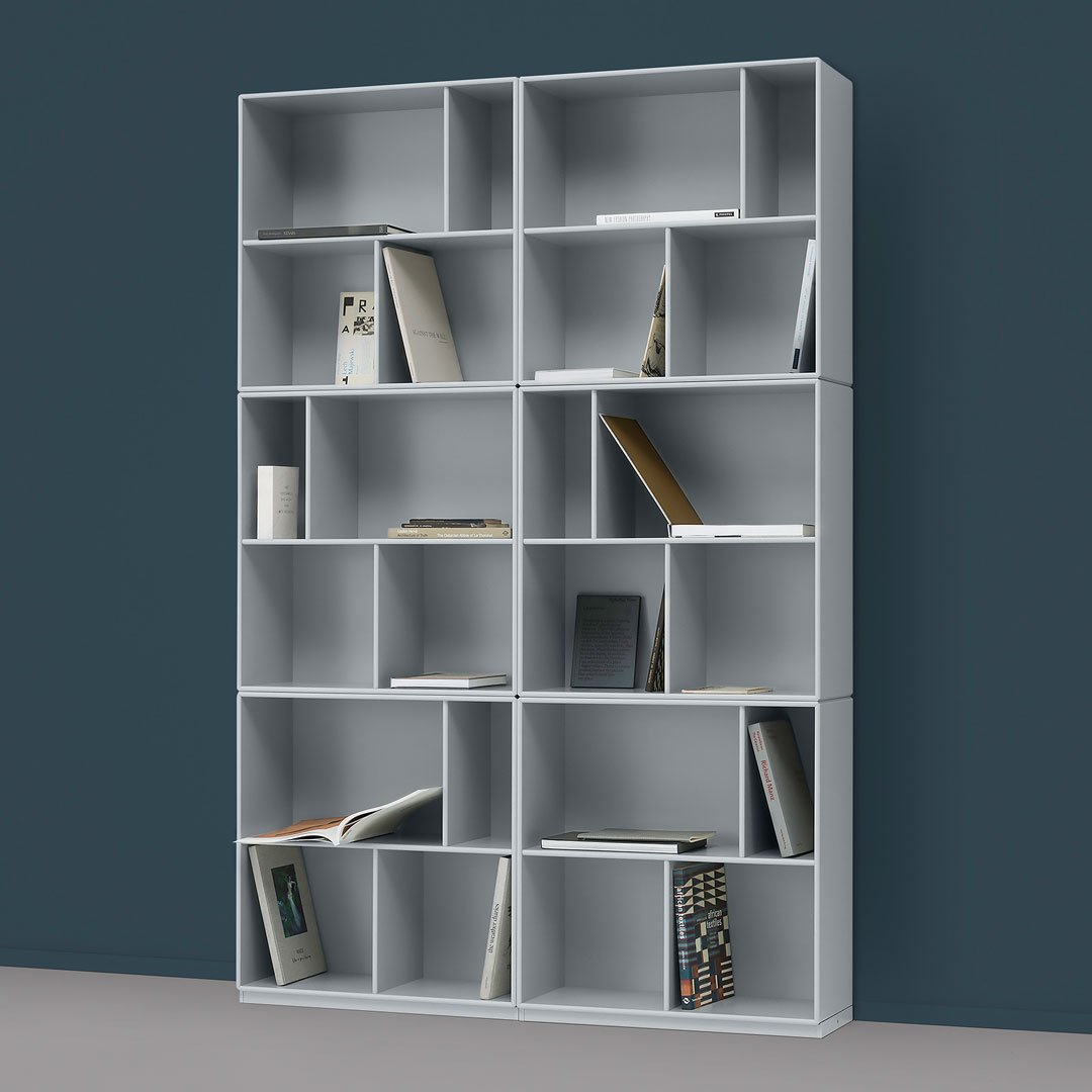 Gray modern bookshelf with a sleek modular design and open compartments, set against a dark teal wall.
