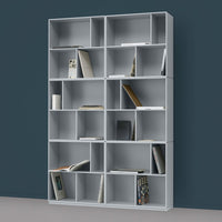 Gray modern bookshelf with a sleek modular design and open compartments, set against a dark teal wall.