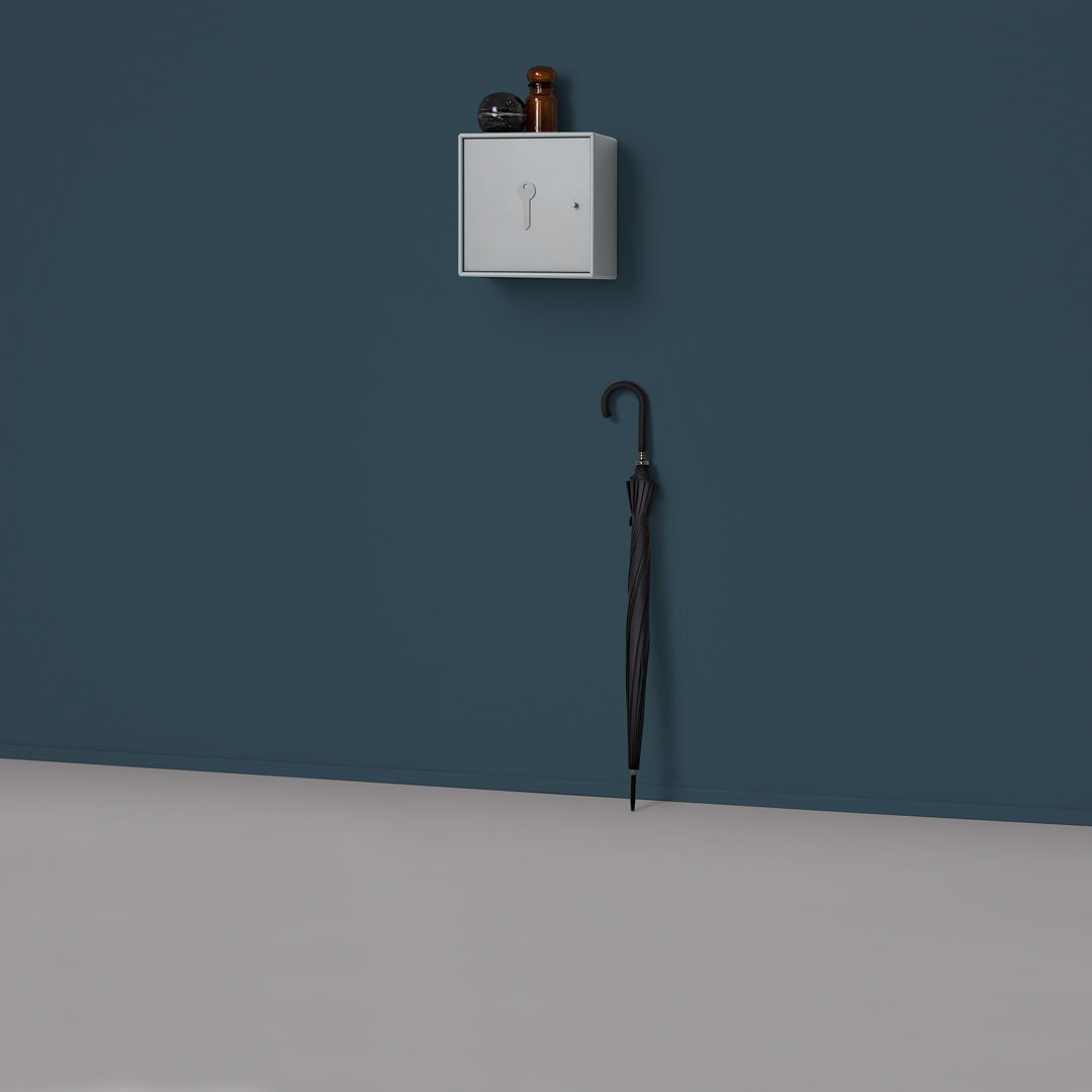 Gray wall-mounted box and black umbrella against a deep blue wall, featuring a smooth gray floor for contrast.