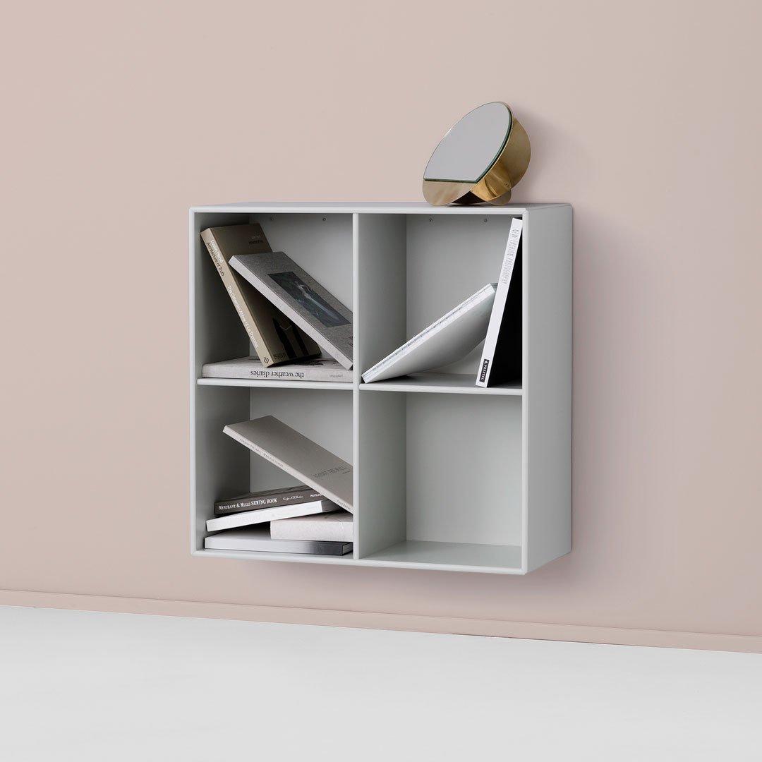 Gray wall-mounted bookshelf with four compartments, showcasing a minimalist design against a soft pink backdrop.