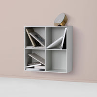 Gray wall-mounted bookshelf with four compartments, showcasing a minimalist design against a soft pink backdrop.