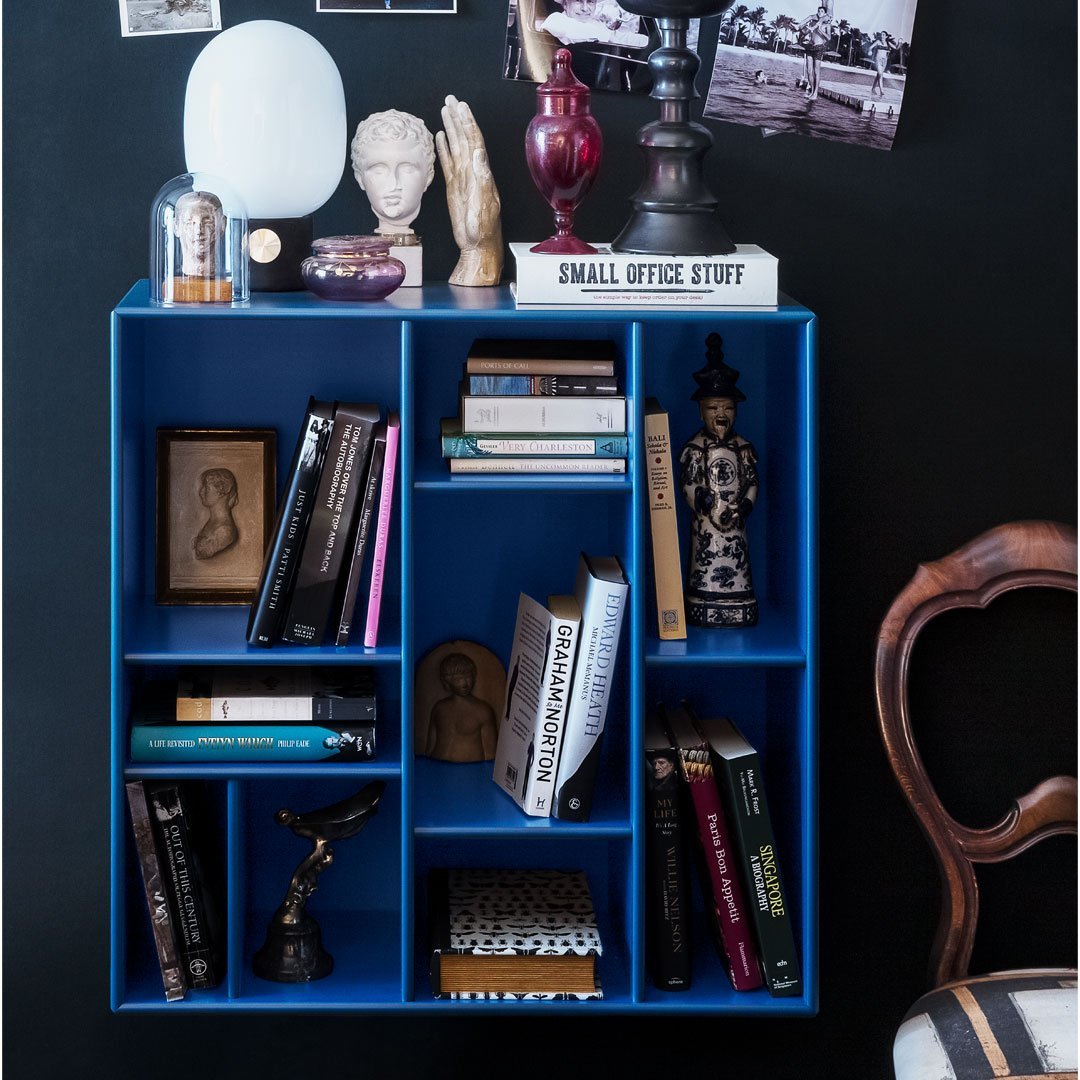 Vibrant blue bookshelf showcasing assorted books and decorative items against a dark wall. Modern and stylish design elements.