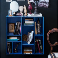 Vibrant blue bookshelf showcasing assorted books and decorative items against a dark wall. Modern and stylish design elements.