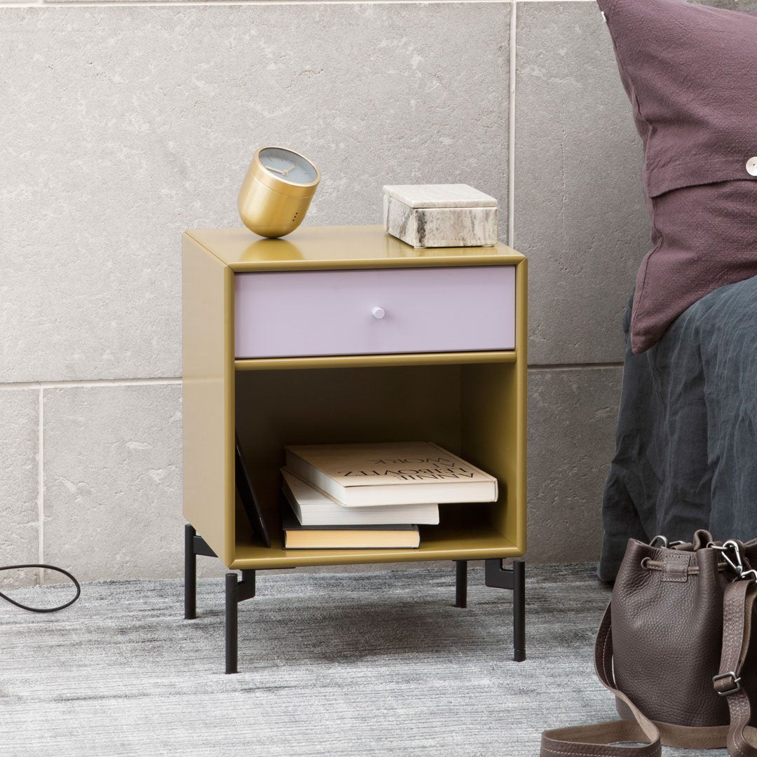 Stylish nightstand in olive green and lavender with a sleek design, featuring black metal legs and simple patterns.