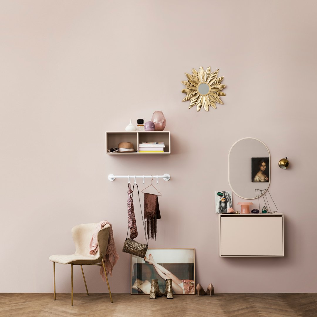 "Soft pink wall, beige chair, gold accents, and pastel decor create a warm, inviting atmosphere with elegant patterns."