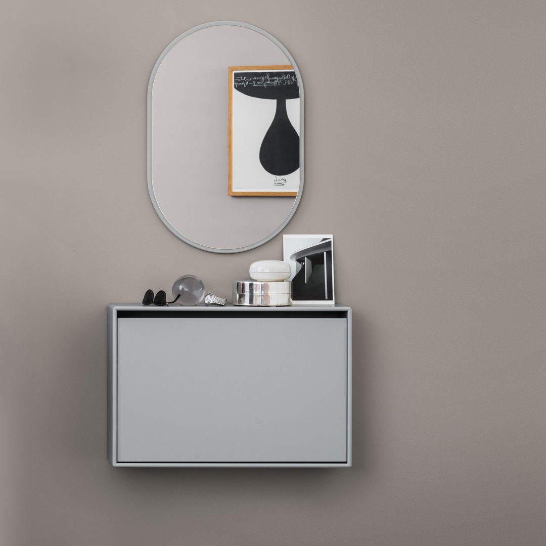 Gray wall-mounted cabinet with a round mirror, surrounded by black and white decor against a taupe wall backdrop.