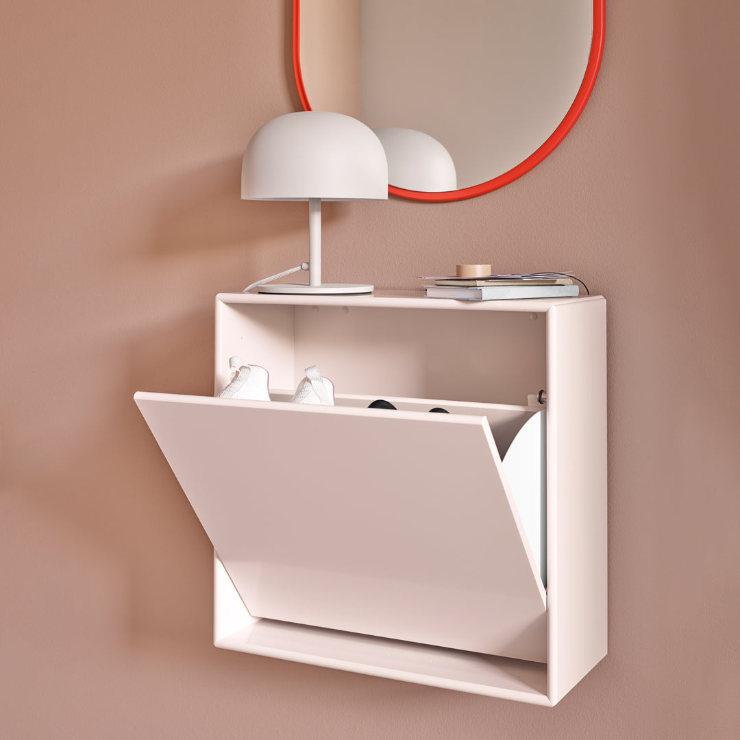 White shoe cabinet against a soft pink wall, featuring a sleek design with a glossy white finish and a round mirror with orange trim.