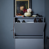 Gray shoe cabinet with sleek design, displayed against a deep blue wall featuring vibrant floral accents and decorative items.