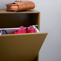 Stylish tan bag atop a sleek olive cabinet with vibrant red suede shoes peeking from a white drawer.
