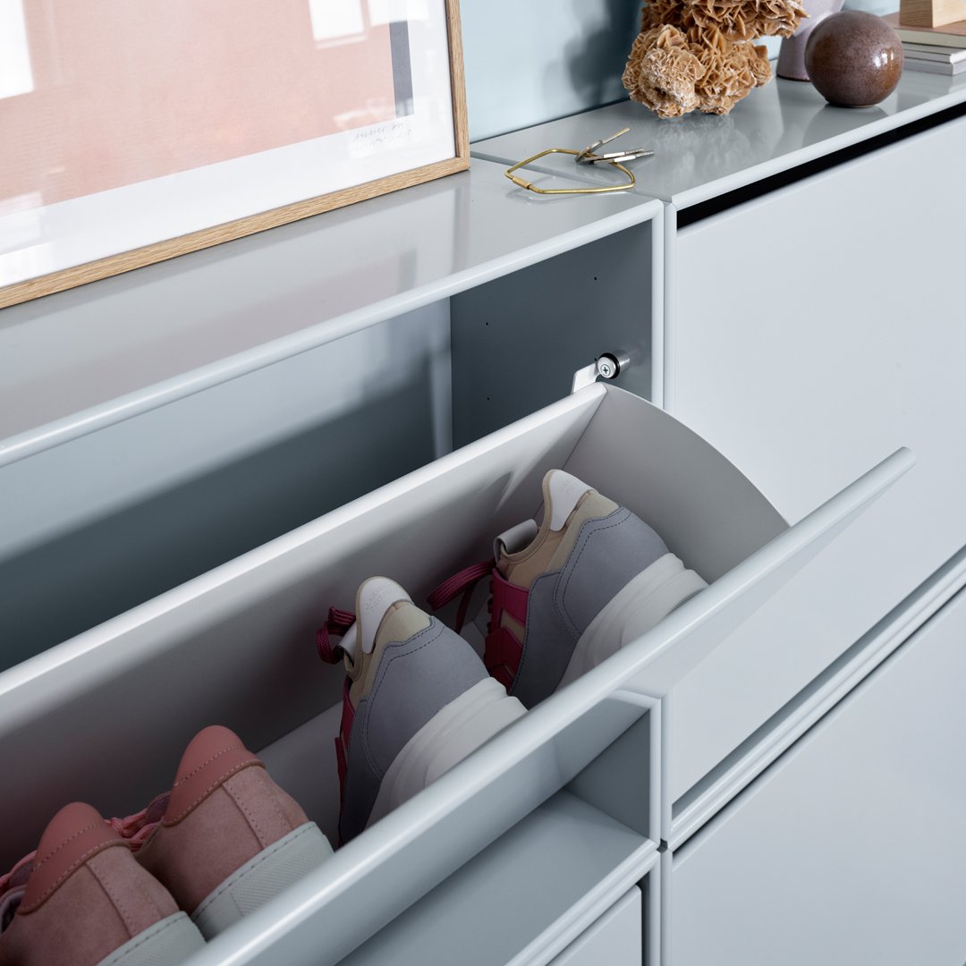 Gray and pink sneakers displayed in a sleek white drawer with minimalist design and a light blue background.
