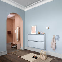Blue and peach walls with pastel accents; modern storage unit, textured rugs, and neutral decor complete the stylish entryway.