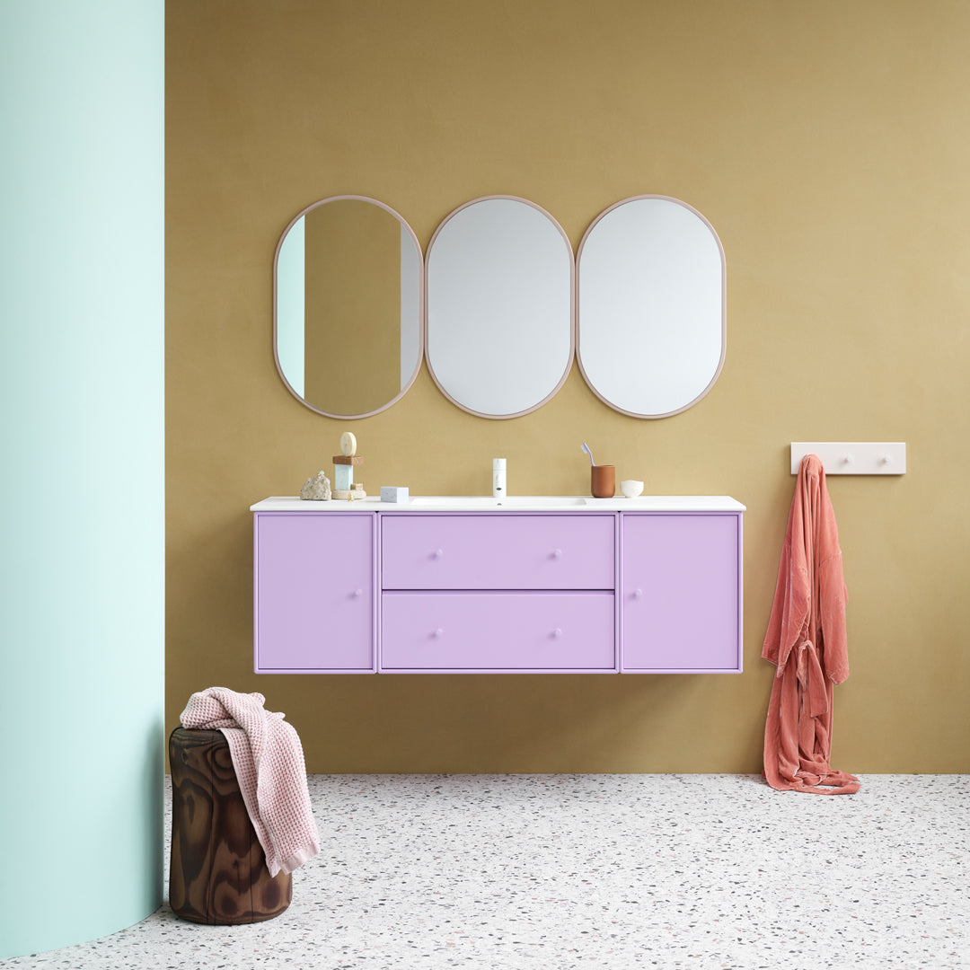 "Lavender cabinet with white top, mint green column, pink towel, and neutral beige walls create a modern, vibrant aesthetic."