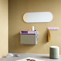 Stylish wall-mounted cabinet in grey and pastel purple, paired with a mint green stool and warm beige wall.
