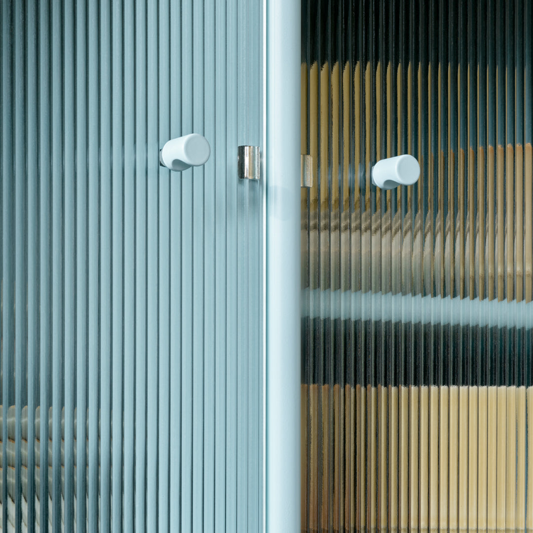 Textured glass cabinet doors in blue, amber, and clear patterns with sleek white knobs. Modern and stylish design.