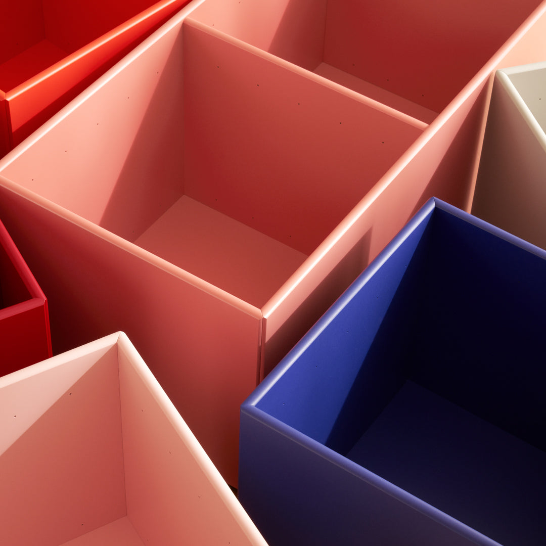 Colorful storage bins in shades of red, pink, and blue with smooth finishes and minimalist designs.