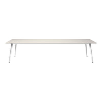 Modern rectangular table in a light beige surface with sleek white metal legs, creating a minimalist aesthetic.