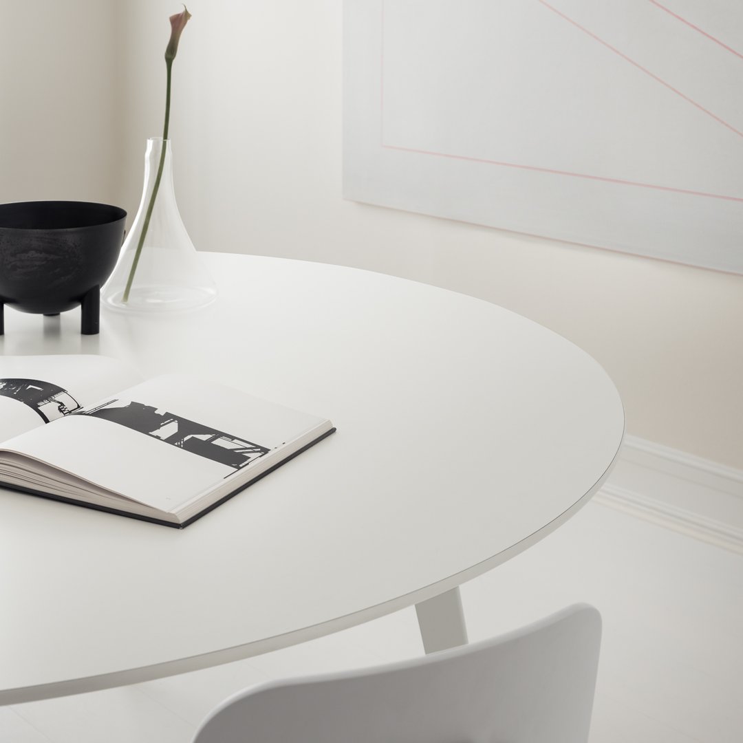 White round table, black bowl, transparent vase, and monochrome book on a neutral-toned background. Elegant minimalist design.