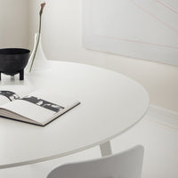 White round table, black bowl, transparent vase, and monochrome book on a neutral-toned background. Elegant minimalist design.