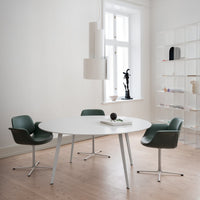 Modern design featuring a round white table, green leather chairs, and neutral walls with wood flooring.
