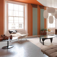 Modern living room with orange, teal, and grey color scheme featuring striped wall patterns and stylish decor elements.