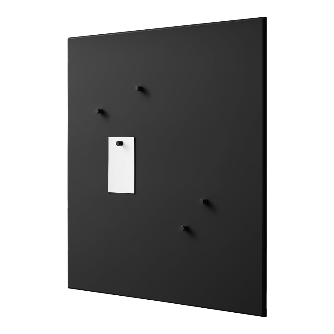 Black wall panel with matte finish, featuring four black hooks and a white rectangular note holder for contrast.