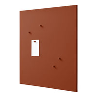 Rust-colored wall panel with a smooth matte finish and contrasting white rectangular tag. Features four small pegs.