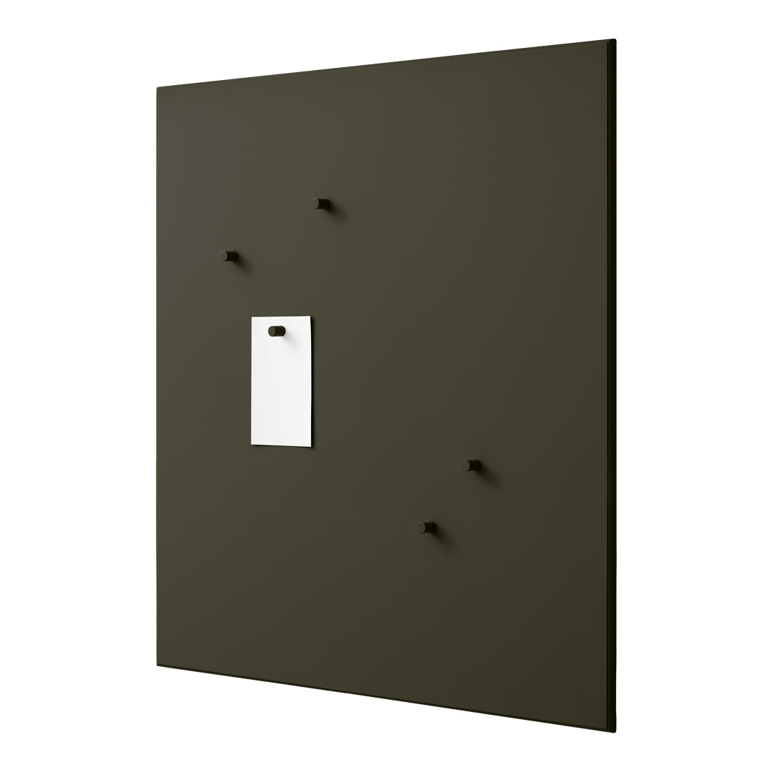 Olive green wall panel with four black pegs and a white note holder, featuring a minimalist design.
