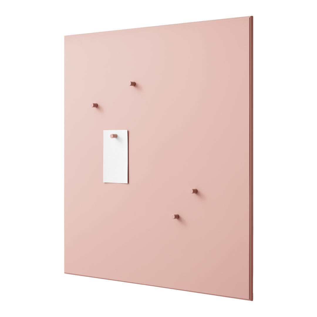 Pink wall panel with five matching hooks and a white note holder in simplistic, modern design.