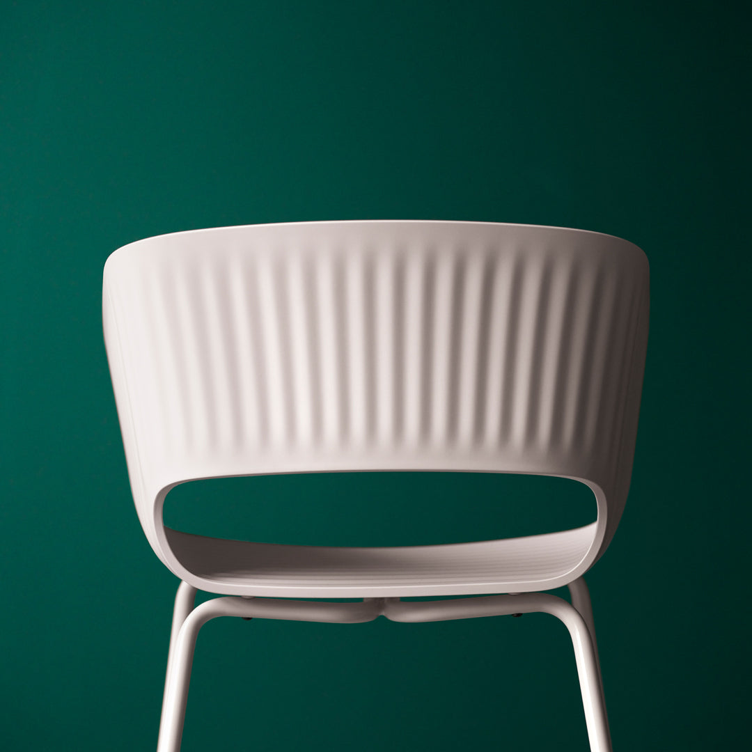 White ribbed chair against a deep green background, highlighting its modern design and elegant contours.